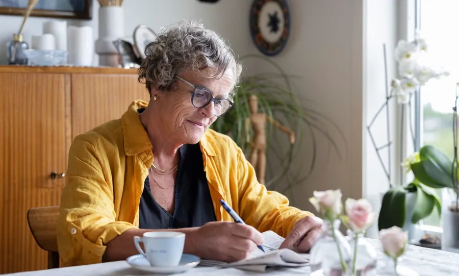 Bild von Gullborg, die mit einer Tasse Kaffee und einer Zeitung an ihrem Tisch sitzt. Blasenprobleme sind bei MS-Patienten keine Seltenheit. Tatsächlich bekommen mehr als 4 von 5 Menschen mit MS irgendwann in ihrem Leben Probleme mit ihrer Blase
