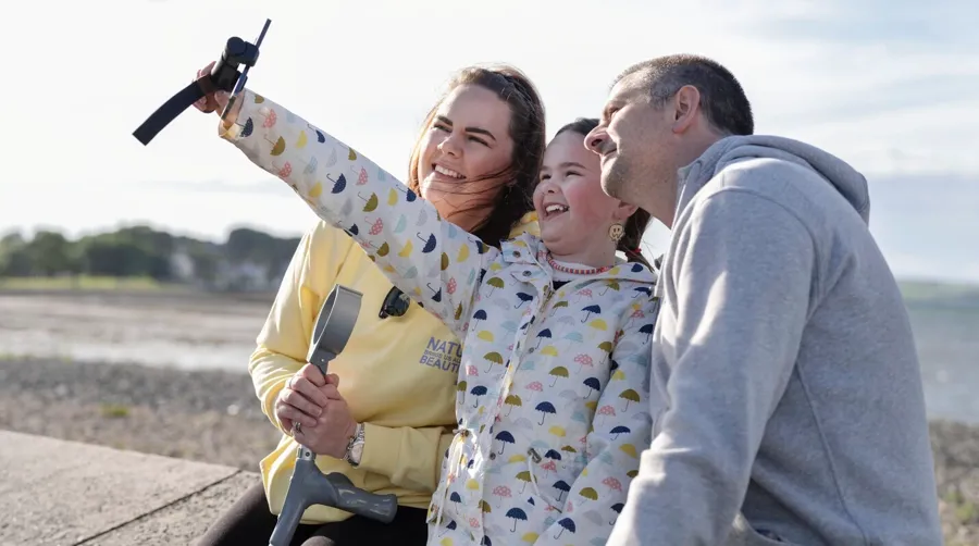 Foto von Sarah und ihrer Familie, die gemeinsam am Strand ein Selfie machen. Sarah brauchte lange, um ihre Blasenprobleme mit ihrer MS-Diagnose in Verbindung zu bringen.