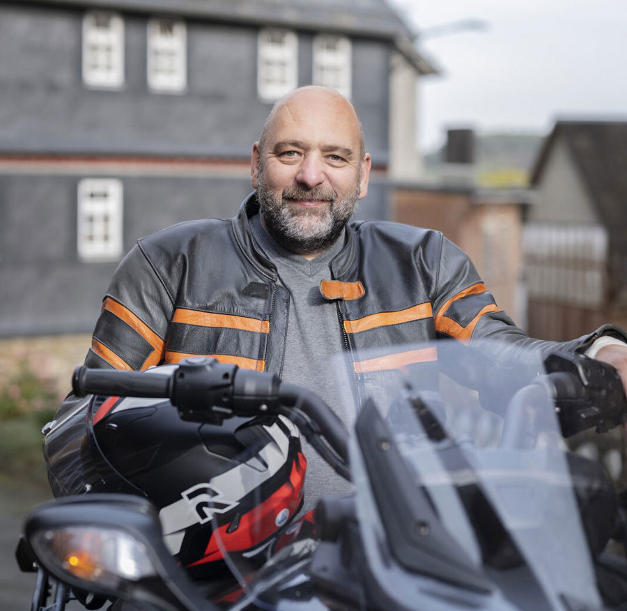 Porträtfoto von Michael auf seinem Motorrad. Michael lebt mit MS und hat Probleme mit seiner Blase. Er stellte fest, dass seine Blase überaktiv war und er häufiger als andere Menschen Wasser lassen musste. 
