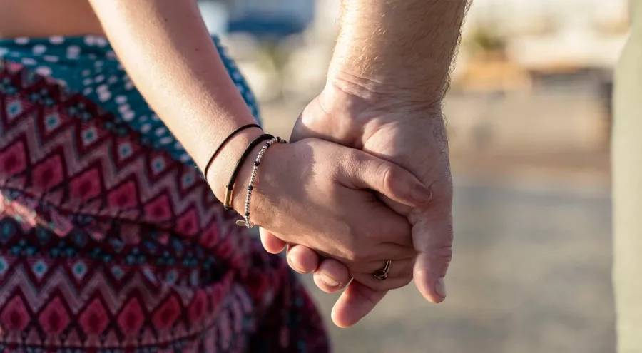 Nahaufnahme eines Paares, das Händchen hält. Andere MS-Symptome wie Müdigkeit, Zittern oder Blasen- und Darmprobleme können das Sexualleben einer Person beeinträchtigen. 